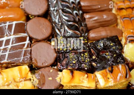 Assortiment de petits morceaux de gâteau avec diverses garnitures et farcis avec différentes garnitures, gâteau spongieux avec chocolat brun et blanc, caramel, confiture, Banque D'Images