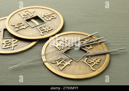 Aiguilles d'acupuncture et pièces chinoises antiques sur table en bois gris, gros plan Banque D'Images