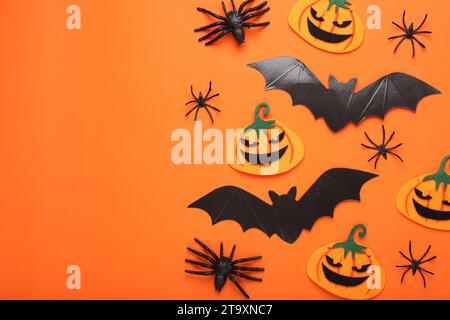 Composition de pose plate avec des chauves-souris en carton, des citrouilles en feutre et des araignées sur fond orange, espace pour le texte. Fête d'Halloween Banque D'Images