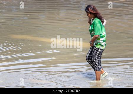 SAMUT PRAKAN, THAÏLANDE, NOVEMBRE 18 2023, Une jeune fille souriante pataugeait dans une rue inondée Banque D'Images