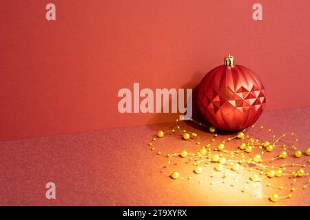 Boule d'ornement rouge de Noël avec décoration dorée sur la table rouge. fond de mur rouge Banque D'Images