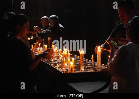 Des gens allumant des bougies à l'intérieur du monastère de Geghard, Arménie Banque D'Images
