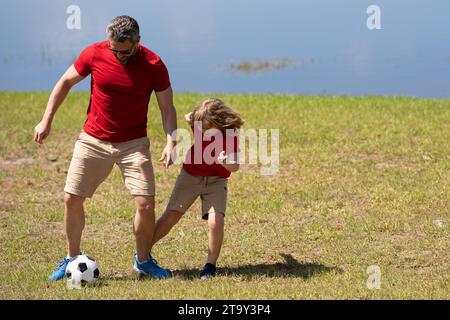 Père et fils font partie d'une famille sportive qui aime jouer au football ensemble. Ils passent les week-ends sur le terrain en pratiquant leurs compétences et ayant Banque D'Images