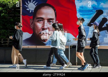 Les passants marchent devant une image de Sun Yat-sen - politicien chinois et révolutionnaire, leader et fondateur du Kuomintang, considéré comme le fondateur de la Chine moderne et démocratique dans le centre-ville de Taipei, Taïwan le 28/11/2023 les résultats d'une enquête récente révèlent une majorité croissante de Taïwanais favorables au maintien permanent du statu quo actuel traversant le détroit, selon un sondage réalisé par le World United Formosans for Independence et l'Association de sécurité nationale de Taïwan. Les données montrent une légère hausse de ce sentiment par rapport aux années précédentes, plus de 44 % des participants préférant cette option. Meanw Banque D'Images