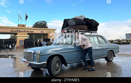 Rafah, Égypte. 27 novembre 2023. Un chauffeur emmenant des Palestiniens à la frontière pour rentrer dans la bande de Gaza se tient près de sa voiture au poste frontière de Rafah. Peu d'endroits sont aussi symboliquement chargés dans la guerre de Gaza que le poste frontière égyptien de Rafah. (À dpa 'atteindre la frontière : une visite au point de passage de Rafah') crédit : Johannes Sadek/dpa/Alamy Live News Banque D'Images