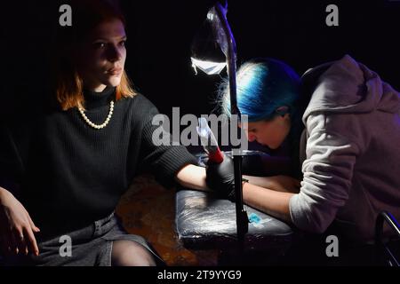 Zaporizhzhia, Ukraine. 25 novembre 2023. Un tatoueur vu travailler sur un client pendant le festival de tatouage caritatif «Walk-In Day» à Zaporizhzhia. Le festival de tatouage caritatif 'Walk-In Day' a eu lieu dans la plate-forme créative 'Mlinn' à Zaporizhzhia. Le but du Festival est de collecter des dons pour l'école de drones militaires Zaporizhzhia. L'espace de bataille ukrainien présente l'utilisation la plus intensive de drones dans un conflit militaire de l'histoire, marquant un changement dans les tactiques et la technologie de guerre. (Photo Andriy Andriyenko/SOPA Images/Sipa USA) crédit : SIPA USA/Alamy Live News Banque D'Images