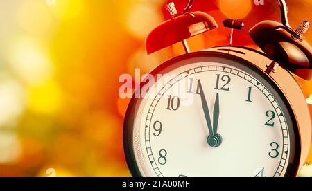 Vintage réveil montre à minuit. C'est douze heures, Noël et vacances, bokeh bonne année concept festif sur la lumière d'arrière-plan flou Banque D'Images