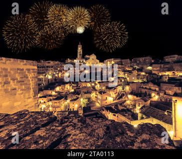 Vue panoramique des pierres typiques (Sassi di Matera) et l'église de Matera la nuit, avec lumière de feux d'artifice de célébration scintillant abstrait doré, concept festif de vacances joyeuses de nouvel an Banque D'Images