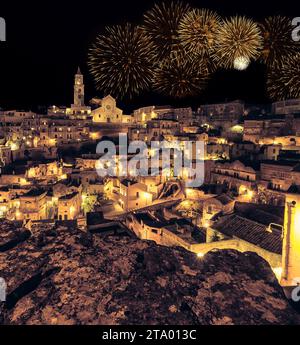 Vue panoramique des pierres typiques (Sassi di Matera) et l'église de Matera la nuit, avec lumière de feu d'artifice de célébration scintillant abstrait doré, f Banque D'Images