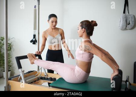 Entraîneur personnel expliquant au client comment faire de l'exercice dans une machine spéciale pour renforcer les muscles du tronc Banque D'Images