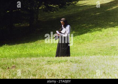 Comté de Gorj, Roumanie, 2000. Femme âgée seule sur un terrain lisant d'un livre de prières. Banque D'Images