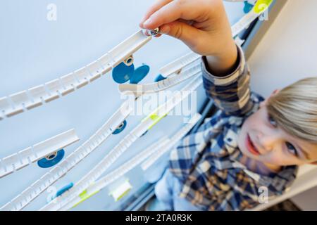 28 novembre 2023, Bavière, Nuremberg : Henri, 6 ans, joue avec le jeu de marbre Gecko Run de Franckh-Kosmos lors de la conférence de presse annuelle de l'Association allemande de vente au détail de jouets (BVS) et de l'Association allemande de l'industrie du jouet (DVSI). Le jouet peut être attaché à n'importe quelle surface lisse et est sur la liste des 'Top 10 Toys 2023' publié par le BVS. Le DVSI et le BVS donnent un aperçu des importantes affaires de Noël et des chiffres actuels pour les derniers mois. Photo : Daniel Karmann/dpa Banque D'Images