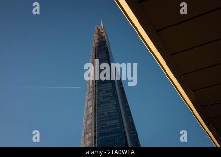 Regardant vers le haut le Shard, Londres, le plus haut bâtiment de Grande-Bretagne avec traînée de vapeur de jet volant haut traversant le ciel. Banque D'Images