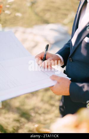 Le marié met sa signature dans le registre du mariage. Rogné. Sans visage Banque D'Images