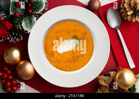 Crème de carotte et de citrouille avec crème et noix. Repas de Noël servis sur une table décorée de motifs de Noël. Banque D'Images