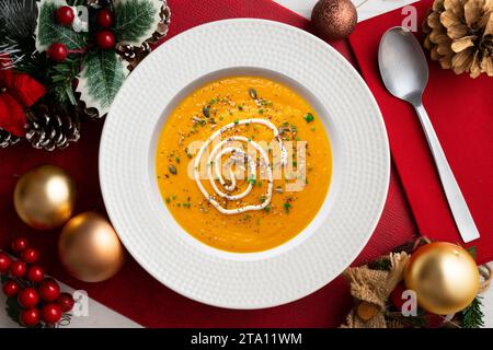 Crème de carotte et de citrouille avec crème et noix. Repas de Noël servis sur une table décorée de motifs de Noël. Banque D'Images