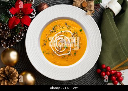 Crème de carotte et de citrouille avec crème et noix. Repas de Noël servis sur une table décorée de motifs de Noël. Banque D'Images