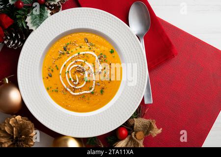 Crème de carotte et de citrouille avec crème et noix. Repas de Noël servis sur une table décorée de motifs de Noël. Banque D'Images