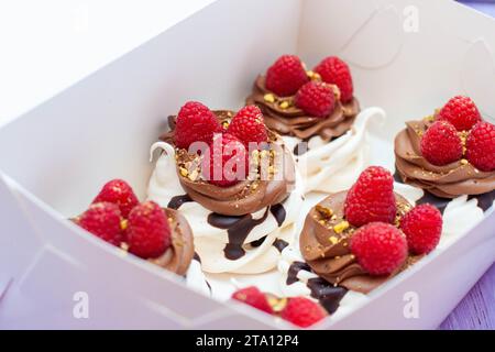 Mini gâteaux à la crème fouettée, chocolat, meringue et framboises fraîches. Affiche de confiserie pour café ou restaurant Banque D'Images
