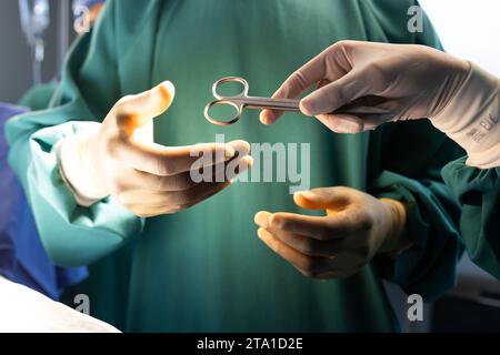 Mains de chirurgiens masculins et féminins divers avec outil chirurgical en salle d'opération hospitalière Banque D'Images