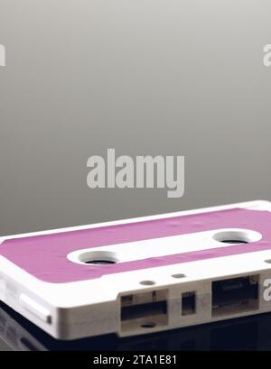 Gros plan d'une cassette blanche et rose avec espace de copie sur fond gris avec réflexion Banque D'Images
