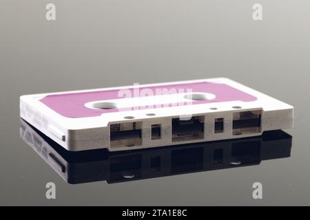 Gros plan de cassette blanche et rose sur fond gris avec réflexion Banque D'Images