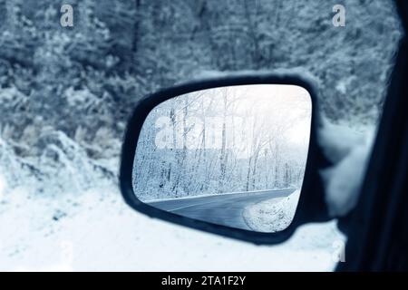 La route hivernale se reflète dans le rétroviseur de la voiture. Gros plan. Banque D'Images