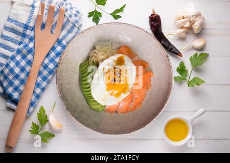 Donburi de saumon teriyaki avec œuf au plat, avocat, oignon, poivron rouge et autres légumes. Plat typiquement japonais. Banque D'Images