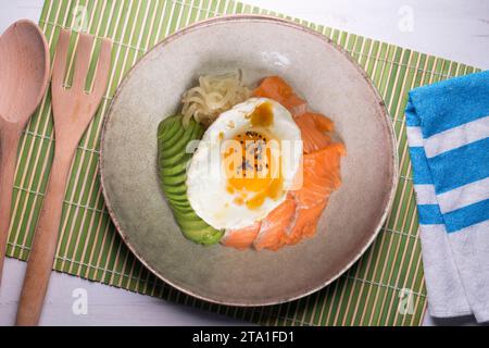 Donburi de saumon teriyaki avec œuf au plat, avocat, oignon, poivron rouge et autres légumes. Plat typiquement japonais. Banque D'Images