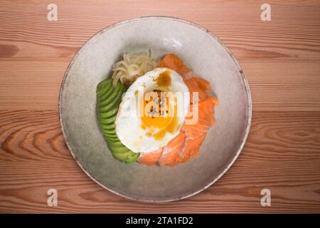 Donburi de saumon teriyaki avec œuf au plat, avocat, oignon, poivron rouge et autres légumes. Plat typiquement japonais. Banque D'Images