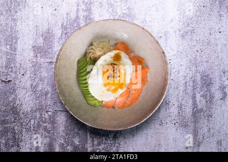 Donburi de saumon teriyaki avec œuf au plat, avocat, oignon, poivron rouge et autres légumes. Plat typiquement japonais. Banque D'Images