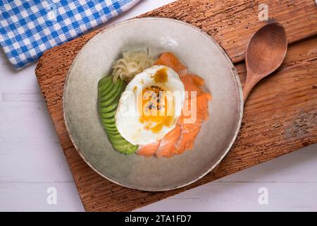 Donburi de saumon teriyaki avec œuf au plat, avocat, oignon, poivron rouge et autres légumes. Plat typiquement japonais. Banque D'Images