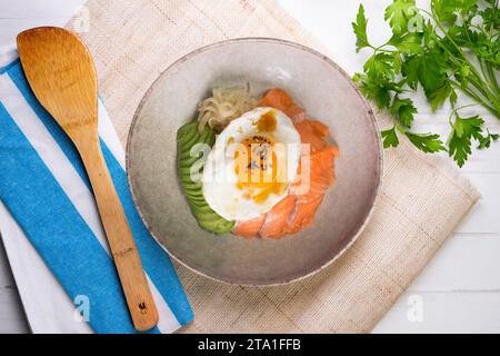 Donburi de saumon teriyaki avec œuf au plat, avocat, oignon, poivron rouge et autres légumes. Plat typiquement japonais. Banque D'Images