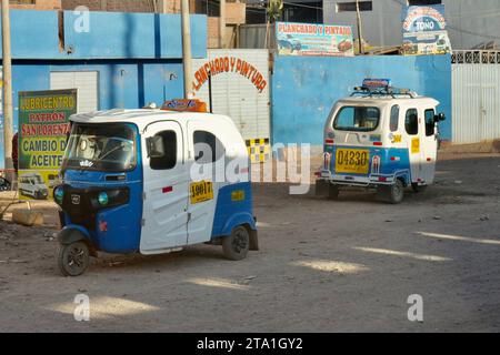 Tuktuks garé dans la rue avec des bâtiments derrière. Puno, Pérou, 8 octobre 2023. Banque D'Images