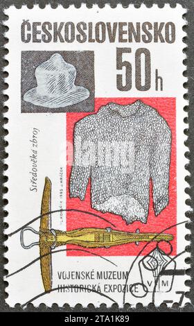 Timbre-poste annulé imprimé par la Tchécoslovaquie, qui montre casque, chemise de courrier et arbalète, expositions du Musée militaire, vers 1985. Banque D'Images