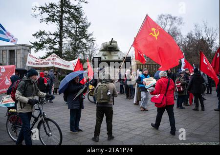 25.11.2023, Berlin, Deutschland, Europa - im Vorfeld einer Friedensdemonstration steht ein Demonstrant mit roter sowjetischer Flagge am Sowjetischen Ehrenmal im Ortsteil Tiergarten mit einem T-34 Panzer im hintergrund. Einige tausend Menschen demonstrieren am Brandenburger Tor im Berliner Bezirk Mitte fuer den Frieden unter dem Titel Nein zu Kriegen- Ruestungswahnsinn stoppen - Zukunft friedlich und gerecht gestalten . Eine der zentralen Forderungen der Kundgebung sind Verhandlungen mit Russland. Auf der Demonstration sprachen neben der Hauptrednerin und ehemaligen Linken-Politikerin Sahra Wag Banque D'Images