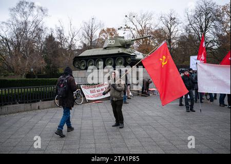 25.11.2023, Berlin, Deutschland, Europa - im Vorfeld einer Friedensdemonstration steht ein Demonstrant mit roter sowjetischer Flagge am Sowjetischen Ehrenmal im Ortsteil Tiergarten mit einem T-34 Panzer im hintergrund. Einige tausend Menschen demonstrieren am Brandenburger Tor im Berliner Bezirk Mitte fuer den Frieden unter dem Titel Nein zu Kriegen- Ruestungswahnsinn stoppen - Zukunft friedlich und gerecht gestalten . Eine der zentralen Forderungen der Kundgebung sind Verhandlungen mit Russland. Auf der Demonstration sprachen neben der Hauptrednerin und ehemaligen Linken-Politikerin Sahra Wag Banque D'Images