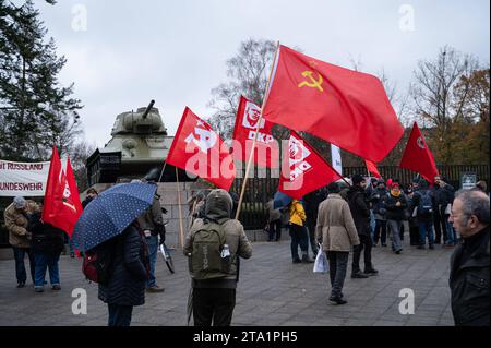 25.11.2023, Berlin, Deutschland, Europa - im Vorfeld einer Friedensdemonstration steht ein Demonstrant mit roter sowjetischer Flagge am Sowjetischen Ehrenmal im Ortsteil Tiergarten mit einem T-34 Panzer im hintergrund. Einige tausend Menschen demonstrieren am Brandenburger Tor im Berliner Bezirk Mitte fuer den Frieden unter dem Titel Nein zu Kriegen- Ruestungswahnsinn stoppen - Zukunft friedlich und gerecht gestalten . Eine der zentralen Forderungen der Kundgebung sind Verhandlungen mit Russland. Auf der Demonstration sprachen neben der Hauptrednerin und ehemaligen Linken-Politikerin Sahra Wag Banque D'Images