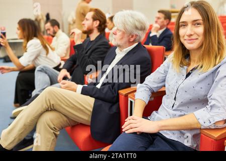 Portrait de femme d'affaires souriante assise par le public dans la chaise au centre des congrès Banque D'Images
