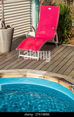 Un transat magenta au bord d'une piscine bleue., St-Leu, Ile de la Réunion, France. Banque D'Images