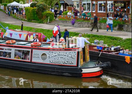 Passager transportant un bateau à voiles passant devant des spectateurs et des visiteurs à un festival de canal. Banque D'Images