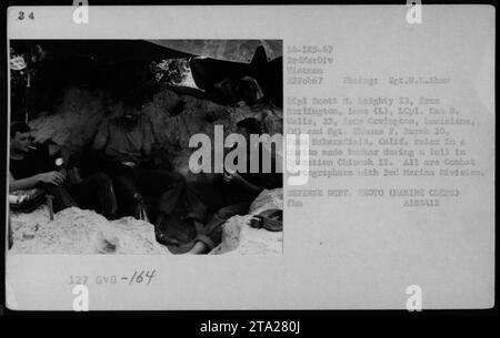 Légende : photographes de combat, le Lcpl Scott M. Leighty, le Lcpl Ken D. Wells et le sergent Thomas F. Burch, tous membres de la 3e Division des Marines, peuvent être vus se détendre dans un bunker sur mesure pendant une pause dans l'opération Chinook II Cette photographie a été prise le 22 février 1967 par le photographe Set.H.L.Shar. Ici, ils documentent les expériences des activités militaires américaines pendant la guerre du Vietnam. Banque D'Images