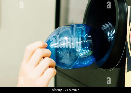 Distributeur automatique de recyclage pour distribuer de l'argent liquide. La main de l'homme met la bouteille en plastique à la machine Banque D'Images