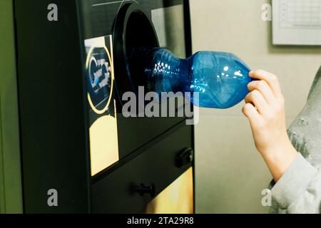 Distributeur automatique de recyclage pour distribuer de l'argent liquide. La main de l'homme met la bouteille en plastique à la machine Banque D'Images