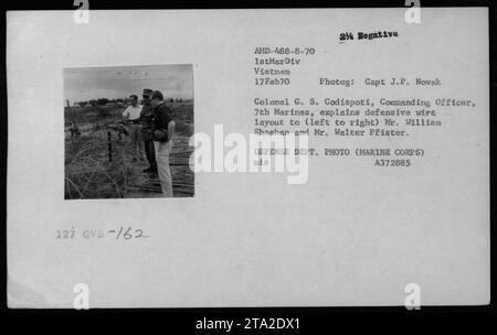 Le colonel G.S. Codispoti, commandant du 7th Marines, informe les civils William Sheehan et Walter Pfister sur la disposition du câble défensif à une base de combat au Vietnam. Cette photographie a été prise le 17 février 1970 par le capitaine J.P. Novak et fait partie de la collection documentant les activités militaires américaines pendant la guerre du Vietnam. Banque D'Images