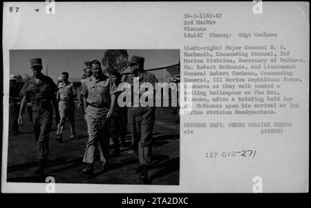 Le major-général B.A. Hochmuth, le secrétaire à la Défense M. Robert McNamara, et le lieutenant-général Robert Cushman marchent vers un hélicoptère à Phu Bai, Vietnam. Ils étaient au quartier général de la 3e Division des Marines après une séance d'information pour M. McNamara à son arrivée. Cette photo a été prise le 9 juillet 1967, pendant la guerre du Vietnam. Banque D'Images