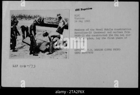 Des membres du Naval Mobile Construction Battalion-10 (Seabees) et des Marines du MABS-12 sont vus sur cette photographie prise le 16 mai 1965. Ils travaillent ensemble à la construction du complexe aéroportuaire de Chu Lai, en posant le premier morceau de tapis. La photo est une photo officielle du corps des Marines des États-Unis, portant le numéro d'identification USMC #A707970. Banque D'Images