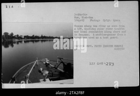 Le corps des Marines patrouille le long de la rivière à Hue, Vietnam, le 16 avril 1965. L'image capture divers trafics fluviaux et la population locale sur le rivage et à Sampans. Un mitrailleur d'un camion est vu servir de garde de bateau. Cette photographie est une photo officielle du ministère de la Défense. Banque D'Images