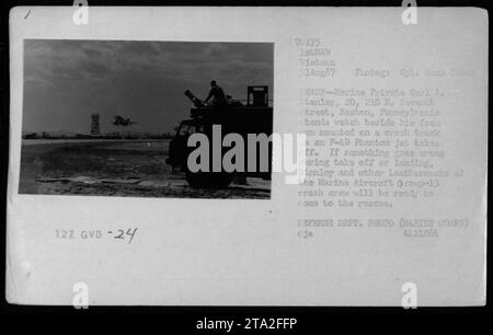 Le soldat Carl A. Stanley se tient à côté de son pistolet à mousse monté sur un camion crash pendant qu'un F-4B Phantom jet décolle. Il est membre de l'équipage de crash du Marine Aircraft Group-13, prêt à intervenir en cas d'urgence pendant le décollage ou l'atterrissage. » Banque D'Images