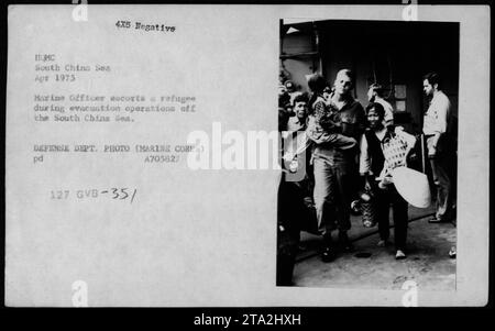 Un officier de marine escorte un réfugié vietnamien lors d'opérations d'évacuation en mer de Chine méridionale. L'image a été prise en avril 1975. Sur la photo, Claudia Cardinale, Nguyen CAO Ky, Rosemary Clooney et Betty Ford rendent visite aux réfugiés. Cette photographie provient de la collection des activités militaires américaines pendant la guerre du Vietnam. Banque D'Images